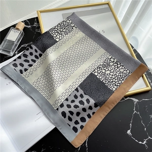 Detailed view of leopard print silk scarf with geometric patterns and bicolor borders