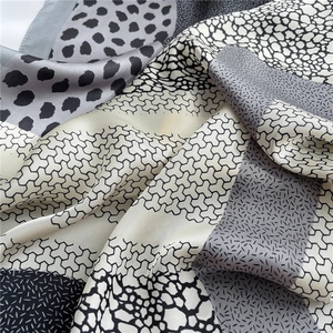 Macro shot of silk satin scarf featuring leopard print and geometric patterns in grayscale