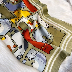 Detail van een zachte zijden sjaal met kleurrijke cartoon katten op groene stof