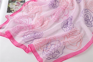 Detailed close-up of pink chiffon square scarf with vibrant rose floral patterns