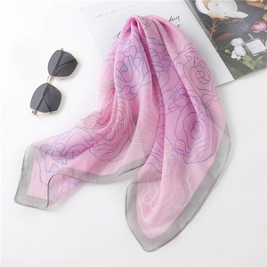 Pink chiffon scarf with blue rose print and elegant gray rolled edges on white surface