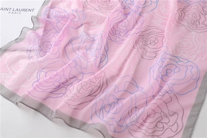 Detail of pink floral silk scarf featuring elegant rose outlines and grey rolled edges