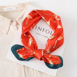 Macro detail of red silk square scarf with flamingo print draped on a cream shirt