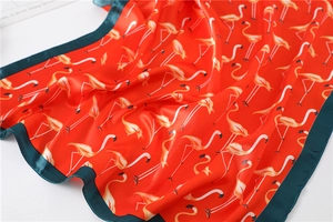 Detail of orange silk scarf with flamingo print and dark green stitched edges