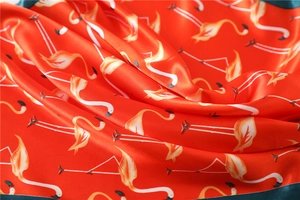 Close-up of silk satin scarf with flamingo print and green contrasting border