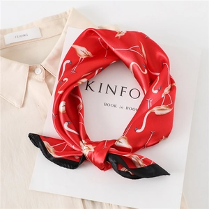 Detail of red satin neck scarf with flamingo print and black border on a cream shirt