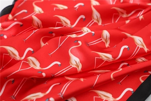 Detail of red satin scarf showing elegant flamingo patterns and smooth silky texture