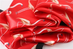 Detail of red silk scarf with white flamingo print showing satin luster and edge stitching