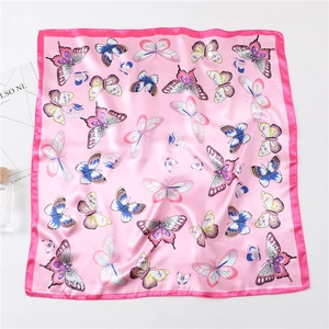 Detailed view of pink silk scarf with butterfly print laid flat on a white background