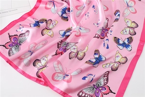 Detailed view of pink silk scarf featuring colorful butterfly patterns and glossy texture