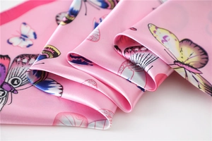 Macro shot of pink silk scarf with butterfly print showing soft satin texture and folds