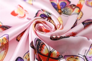 Close-up of pink satin scarf with colorful butterfly print and silky fabric texture