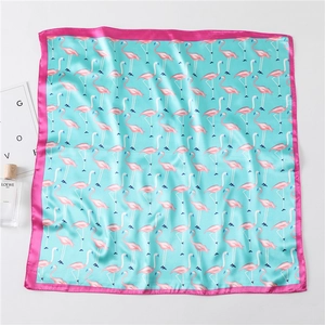 Detail of silk square scarf featuring pink flamingo prints and blue satin texture