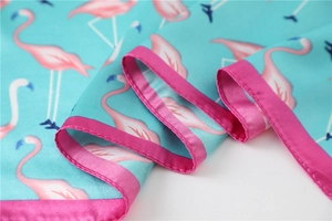 Close-up of mint green silk scarf with pink flamingo print and satin edges