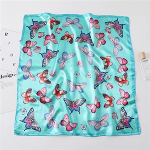 Macro detail of silk scarf featuring vibrant butterfly prints on a peacock blue fabric