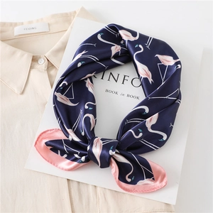 Navy blue silk square scarf with pink flamingo pattern on a beige shirt background