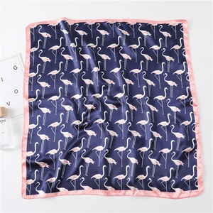 Detail of silk square scarf featuring pink flamingo patterns on navy blue fabric