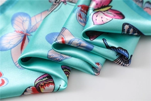 Detailed view of silky butterfly print scarf with elegant mint green satin texture