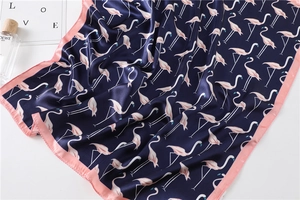 Detail of navy blue silk scarf with flamingo print and pink borders on satin fabric