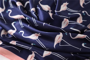 Detailed view of navy silk scarf featuring pink flamingo patterns and smooth satin texture