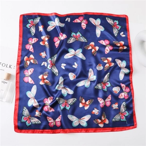 Close-up of butterfly print silk scarf with red border and colorful pattern detail