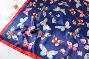 Detail of navy blue butterfly print silk scarf with red border and satin luster finish