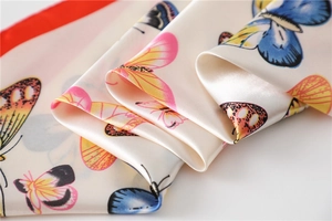 Macro shot of butterfly print silk scarf showing satin texture and colorful details