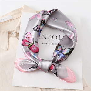 Detail of silk-like butterfly print scarf on neutral shirt with lifestyle magazine
