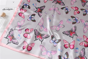 Detail of a square silk scarf with butterfly prints and elegant pink stitched edges