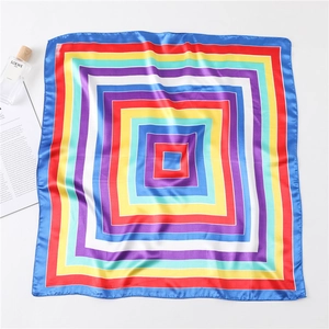 Flat lay of colorful striped satin square scarf with elegant perfume and magazine decor