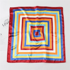 Detail of a square silk scarf featuring a colorful geometric frame design and satin finish