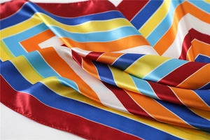 Detail of colorful striped silk scarf showing soft satin texture and rolled hem edges