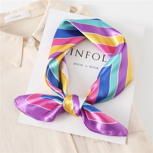 Colorful striped satin square scarf accessory styled on a light beige shirt and white book