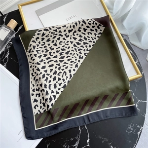 Detail of leopard print and olive green silk scarf flat lay on marble table