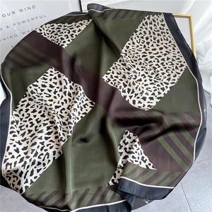 Close-up of leopard print and olive green patchwork silk scarf with elegant black borders