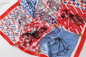 Gros plan sur un foulard en soie avec bordure rouge et motifs pied-de-poule et fleurs