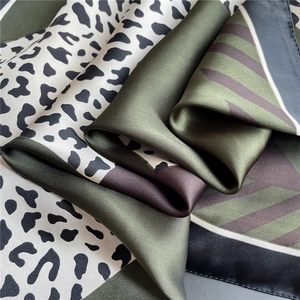 Close-up of leopard print and geometric patterns on a silk satin scarf with elegant drape
