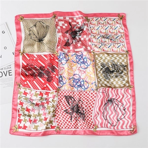 Détail d'un foulard en soie avec motifs floraux, pied-de-poule et bordure rose