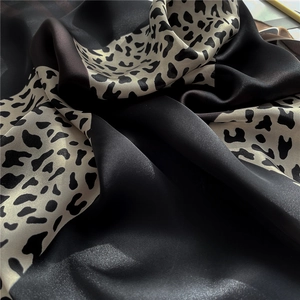 Detailed view of leopard print silk scarf with luxury satin texture and black cream pattern