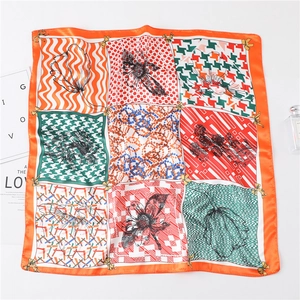 Vue à plat d'un foulard en soie orange avec patchwork pied-de-poule et fleurs