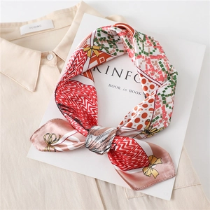 Gros plan d'un foulard en soie imprimé noué en nœud sur un magazine blanc et chemise beige