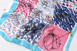 Détail d'un foulard en soie montrant des motifs pied-de-poule, fleurs et texture douce