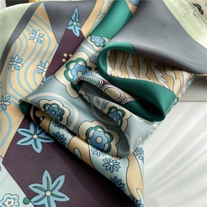 Detailed close-up of smooth satin silk scarf with elegant floral abstract pattern and folds