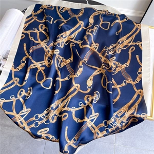 Detail eines Seidenschals mit goldenen Kettenmustern auf dunkelblauem Satin