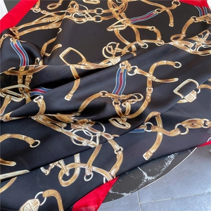 Detailansicht eines Seidenschals mit Vintage-Goldkettenmuster und rotem Rand auf Marmor