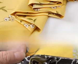 Detail view of yellow floral silk scarf showing premium invisible stitching on the edges