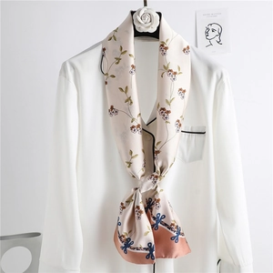 Pink silk-like floral skinny scarf with bow border hanging on a white hanger