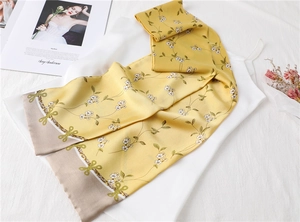 Close-up of thin silk scarf with yellow floral print and elegant brown border detail