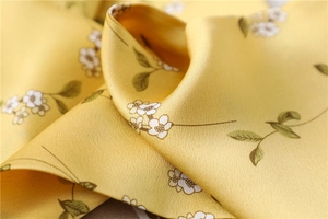Macro view of silky yellow scarf fabric with small white floral print and soft luster