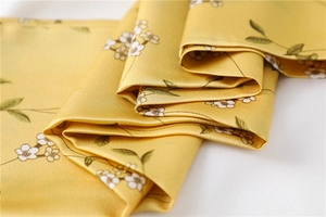 Detail of yellow floral silk scarf fabric showing delicate texture and vibrant prints